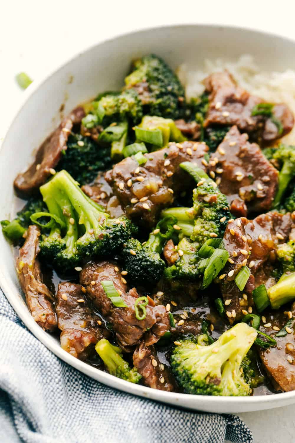 This Beef and Broccoli takes just minutes to throw in the slow cooker. My top five favorite recipes on the blog! Beef and broccoli over rice in a white bowl.