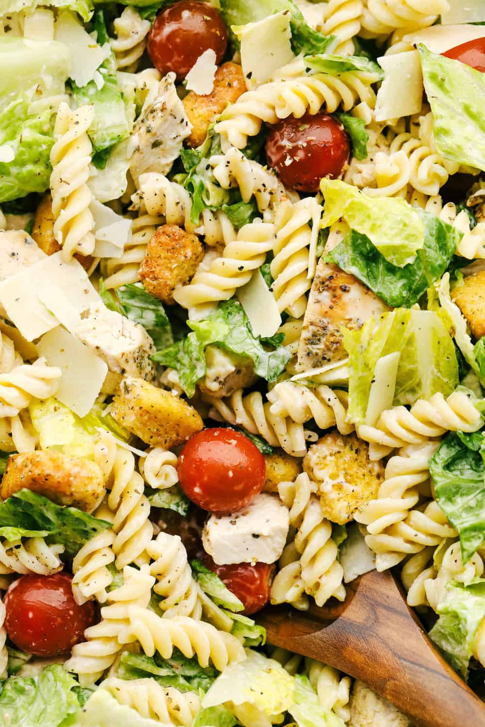 Chicken Caesar Pasta salad is fun twist on the classic! Fresh romaine tossed with chicken, cherry tomatoes, shredded parmesan cheese, croutons and a vegetable pasta adds a fun new texture! Up close picture showing the texture and flavors in the salad.
