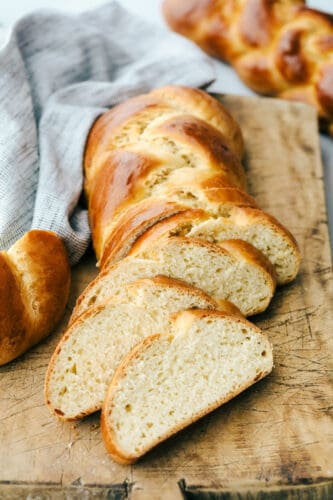 Challah Bread is a rich and fluffy loaf full of flavor. A Jewish traditional loaf, this incredible bread is going to be a favorite in your family baking! Sliced Challah on a breadboard.