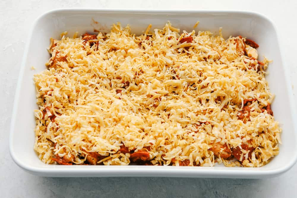 Bubble pizza is a fabulous spin on pepperoni pizza that is easy and crazy good! Soft pillowy biscuits are smothered in sauce, pepperoni, and topped with cheese! Mixture in a 9x13 with cheese on top ready to bake.