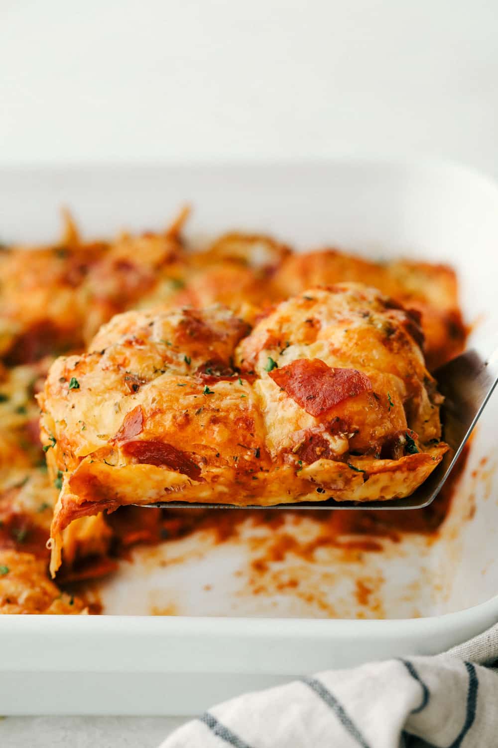 Bubble pizza is a fabulous spin on pepperoni pizza that is easy and crazy good! Soft pillowy biscuits are smothered in sauce, pepperoni, and topped with cheese! Scooping out a slice of Bubble pizza.