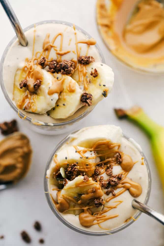 Peanut Butter Banana Smoothie is a rich refreshing drink that is good for you too! Full of protein, vitamins, and minerals use it as a workout recovery drink or a snack. The top of a banana smoothie with fresh cut bananas with a straw in a glass cup.