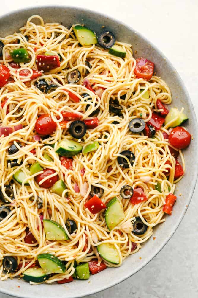 California Spaghetti Salad is a delicious pasta salad filled with fresh veggies and covered in a zesty Italian dressing. With all those flavors and colors making one beautiful and tasty side dish, there is no doubt this will be the hit of your next gathering! California spaghetti salad in a gray bowl.