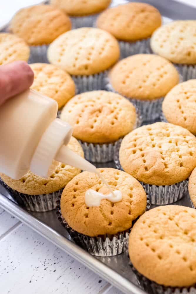 Light, fluffy Tres Leches Cupcakes are drenched in a three milk mixture, just like classic Tres Leches Cake, but in the handheld form! Topped with sweetened whipped cream, a light dusting of cinnamon, and fresh strawberries, these make a wonderful finish to any Mexican dinner! 3 milk mixture soaking into cupcakes