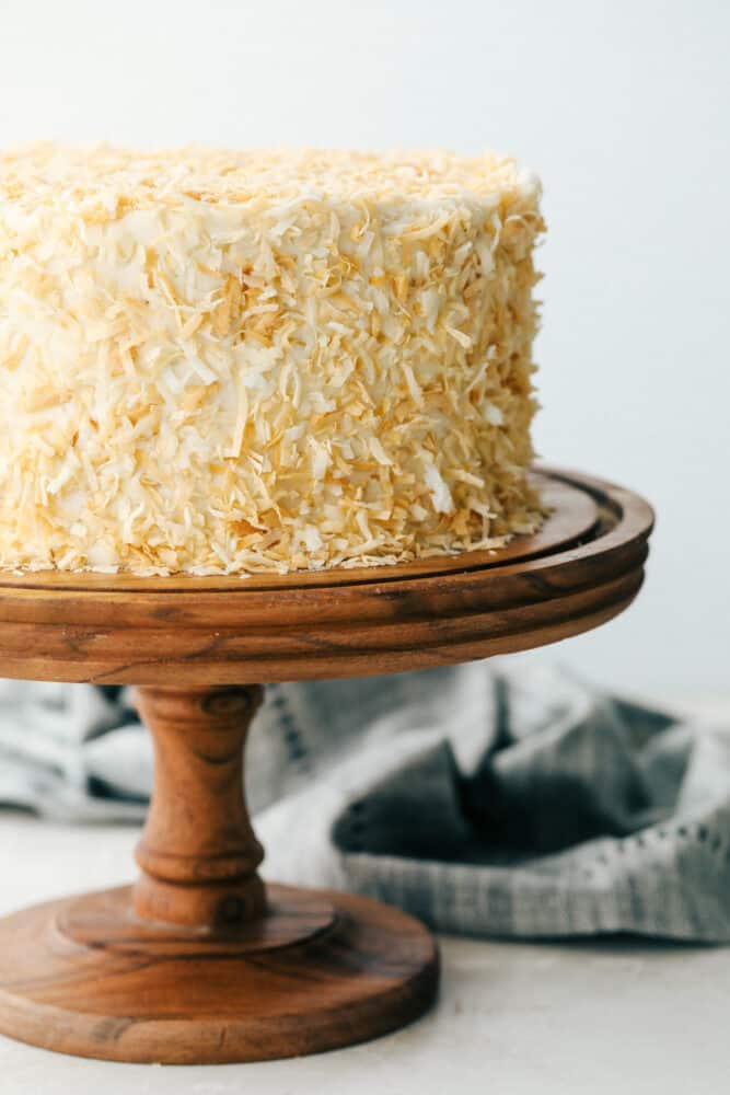 Coconut Cream Cake with Coconut Cream Cheese Frosting is super moist and delicious with the best coconut cream cheese frosting! This cake will be devoured and loved by all! Coconut cake on a pedestal ready to cut.