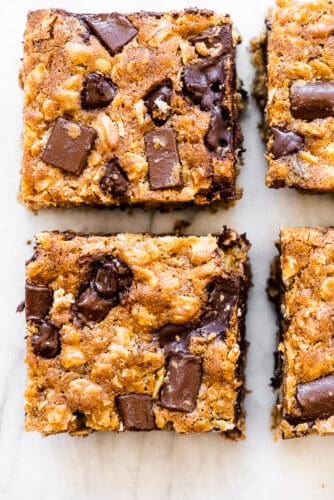 These oatmeal chocolate chip bars are a delicious treat. They're thick and chewy, full of sweet chocolate chips, and perfect for any occasion. Bonus that they're very easy to make! Oatmeal chocolate chip bars on a marble countertop.