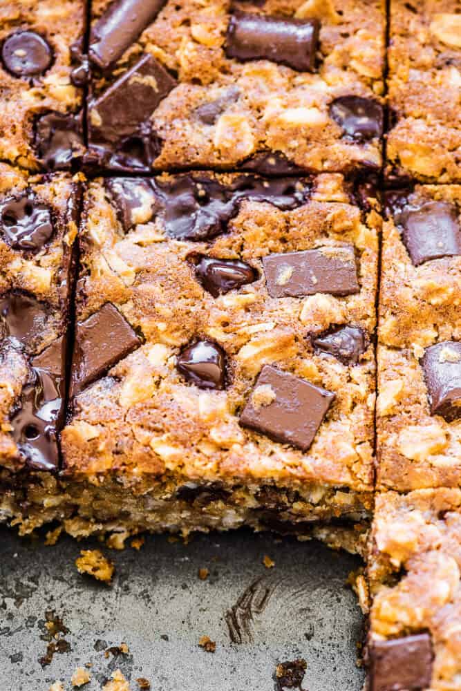 These oatmeal chocolate chip bars are a delicious treat. They're thick and chewy, full of sweet chocolate chips, and perfect for any occasion. Bonus that they're very easy to make! Oatmeal chocolate chip bars in a baking dish with a few missing.