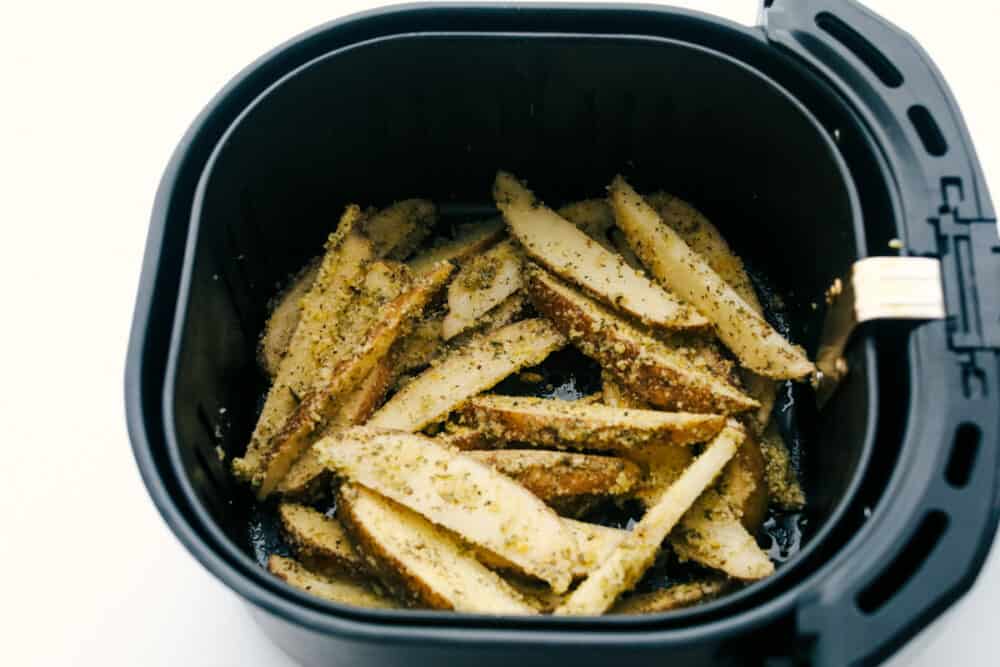 Air Fryer Potato Wedges are crispy and seasoned on the outside and perfectly tender on the inside! These are so insanely delicious you are going to love them! Air fryer basket full of wedges ready to cook.