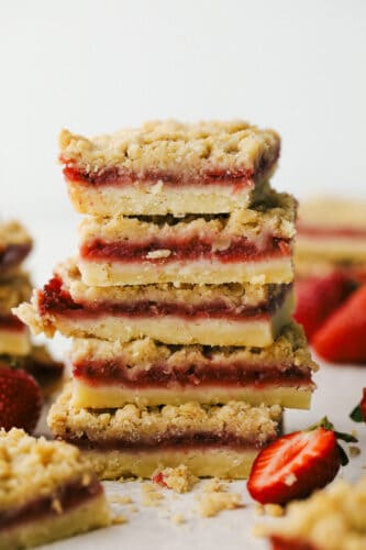 Strawberry Streusel Bars are buttery, sweet and the perfect summertime treat! With a tasty shortbread and mouth watering crumble top, everyone is going to love these! Strawberry streusel bars stacked on top of eachother ready to eat.