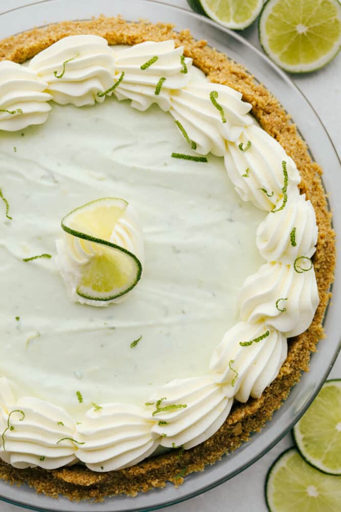 No Bake Key Lime PIe is a slice of tropical heaven. This has a sweet crunchy crust filled with a refreshing, creamy and zippy lime filling perfect for the summer heat! No-bake key lime pie with lime zest decorating the top.