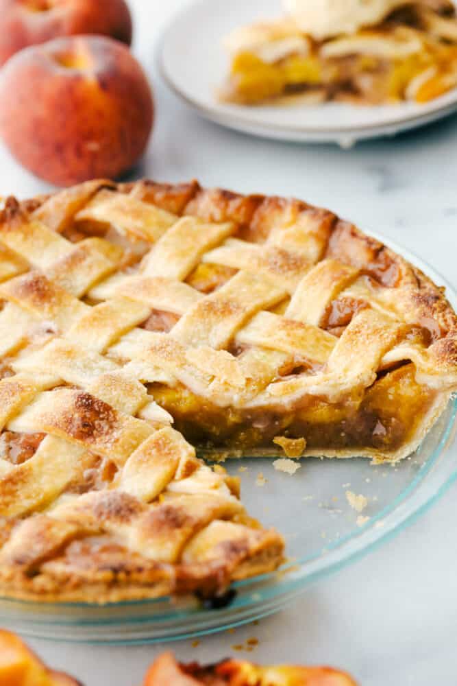 This Homemade Peach Pie is a bit of summer paradise on your plate! Flakey buttery crust is filled with a luscious sweet peach filling that is perfect with a scoop of vanilla ice cream. Peach pie with a slice taken out of it.