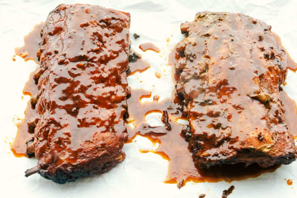 Slow Cooker ribs are going to melt in your mouth and fall off the bone! They are cooked low and slow so they are perfectly tender and then covered in a sauce that's absolutely to die for! Adding extra sauce to the ribs before broiling.