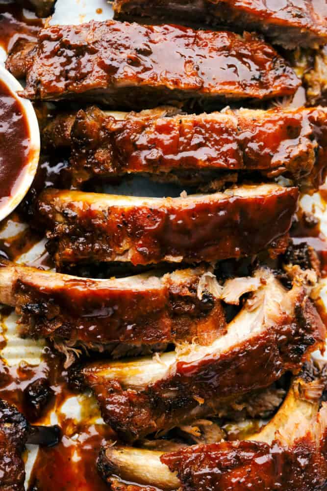 Slow Cooker ribs are going to melt in your mouth and fall off the bone! They are cooked low and slow so they are perfectly tender and then covered in a sauce that's absolutely to die for! Segmented ribs with sauce showing texture.