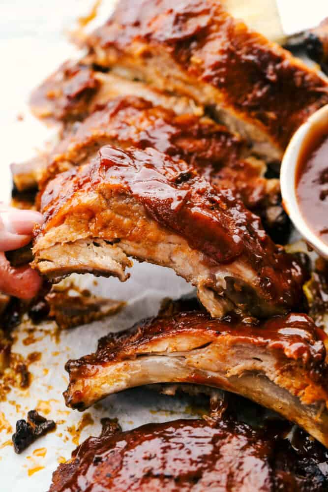 These Slow Cooker ribs are going to melt in your mouth and fall off the bone! They are cooked low and slow so they are perfectly tender and then covered in a sauce that's absolutely to die for! Pulling a rib from others to eat.