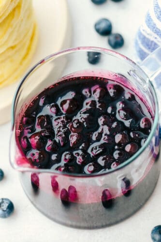 This Homemade Blueberry Syrup will be the best addition to your breakfast lineup. It is sweet, decadent, and you will want to put it on everything! Blueberry syrup in a measuring cup.
