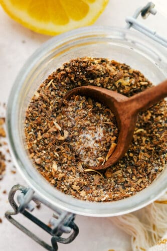 Lemon Pepper Seasoning is a little bit zingy and a little bit peppery, and a whole lot delightful! Making your own lemon pepper is super easy and absolutely delicious. Spooning out a Tablespoon of lemon pepper.
