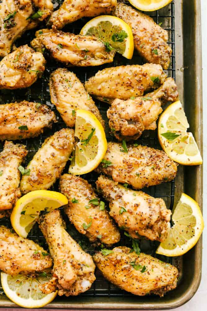 Lemon Pepper Chicken Wings are buttery, zesty, and will WOW at your next family get-together! They are super easy to make and pack delicious flavor in every juicy bite! Lemon Pepper Wings on a baking rack with lemon garnish