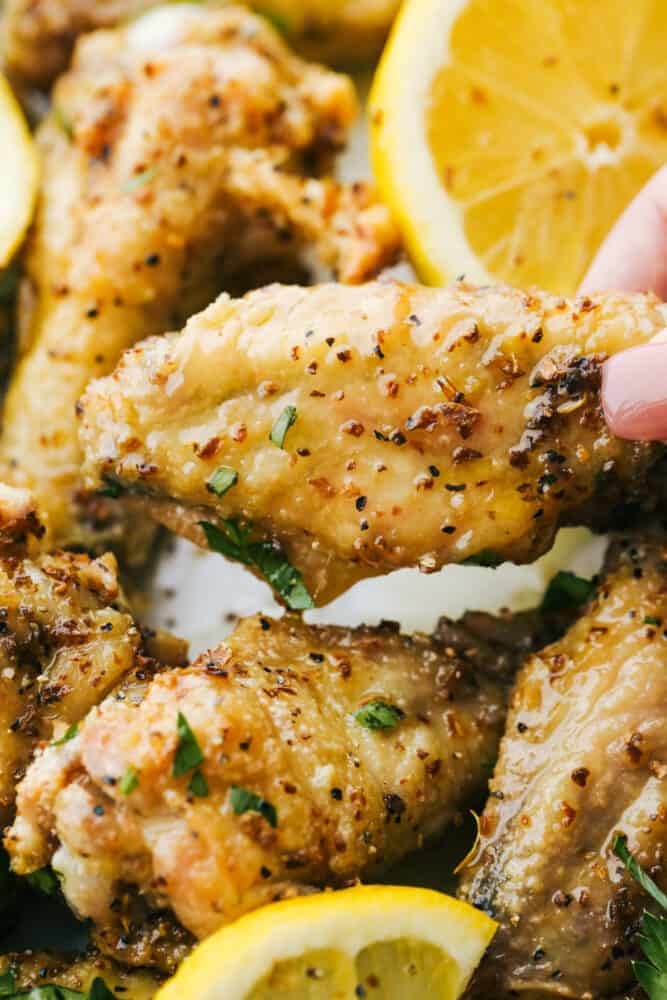 Lemon Pepper Chicken Wings are buttery, zesty, and will WOW at your next family get-together! They are super easy to make and pack delicious flavor in every juicy bite! Holding a Lemon Pepper Chicken Wing