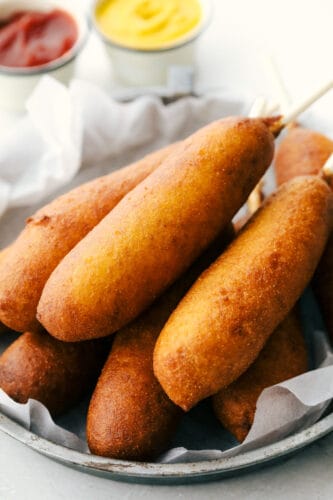 Homemade corn dogs are crispy golden on the outside and perfectly cooked on the inside. These are super easy to make at home and the whole family is going to love how they taste! A plate of golden crisp corn dogs.
