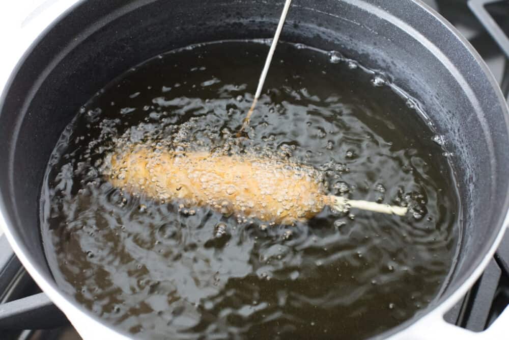 Homemade corn dogs are crispy golden on the outside and perfectly cooked on the inside. These are super easy to make at home and the whole family is going to love how they taste! Frying the corn dogs.