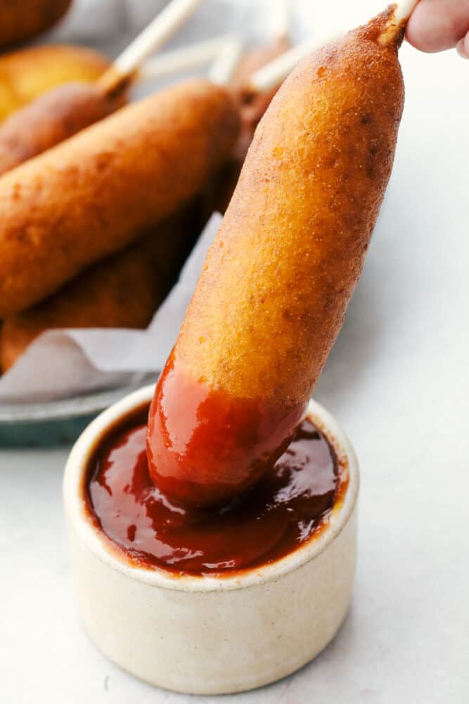 Homemade corn dogs are crispy golden on the outside and perfectly cooked on the inside. These are super easy to make at home and the whole family is going to love how they taste! Dunking a corndog in ketchup.