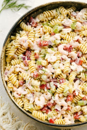 This lovely Shrimp Pasta Salad is going to become your new go-to for summer picnics and potlucks. With tender bits of shrimp, fresh veggies, and the fact that it is so easy to put together and take on the go, it is quickly becoming one of my favorite recipes of the season! Shrimp pasta salad in serving bowl