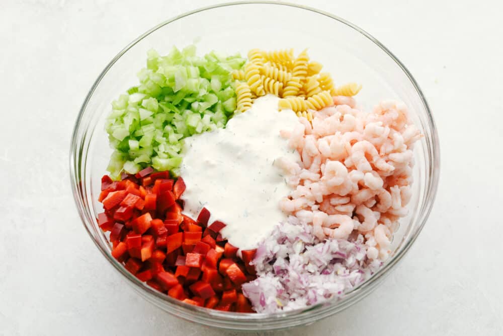 This Shrimp Pasta Salad is going to become your new go-to for summer picnics and potlucks. With tender bits of shrimp, fresh veggies, and the fact that it is so easy to put together and take on the go, it is quickly becoming one of my favorite recipes of the season! Shrimp pasta salad ingredients in bowl before mixing