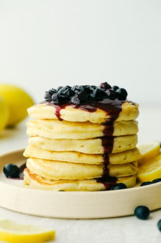 Lemon Ricotta Pancakes are fluffy, tender pancakes that are elevated to a whole new level. The ricotta adds protein and a lightness that is absolutely divine while the lemon gives it a bit of a tangy taste that you are going to love! Stack of Lemon ricotta pancakes with blueberry sauce.