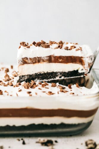 Oreo Lasagna is a no-bake slice of chocolate heaven! Layered with a cream cheese and pudding layer, sandwiched between whipped topping and luscious Oreo crust, it's too die for! Scooping out the chocolate lasagna from a 9x13.