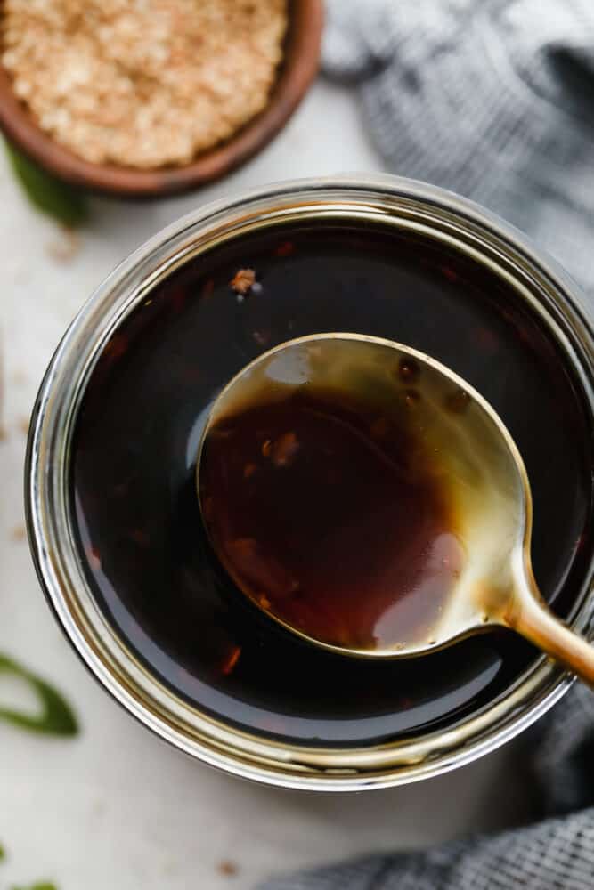 Homemade Teriyaki Sauce is super easy and way better than store-bought! Made with simple ingredients you can pronounce, this is going to become a staple in your family. Scooping out a spoonful of teriyaki sauce from the jar.