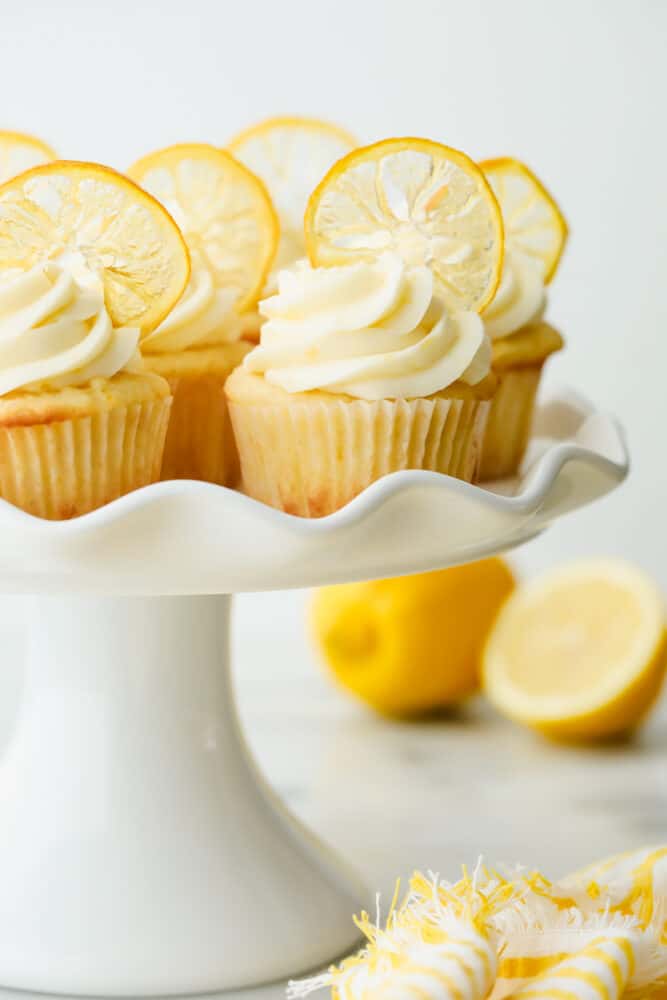 The AMAZING sweet and zesty flavors of these Lemon Cupcakes will have you hooked! Fresh lemon adds a pinch of summer to a classic, decadent treat. Lemon cupcakes with garnish on a serving platter.