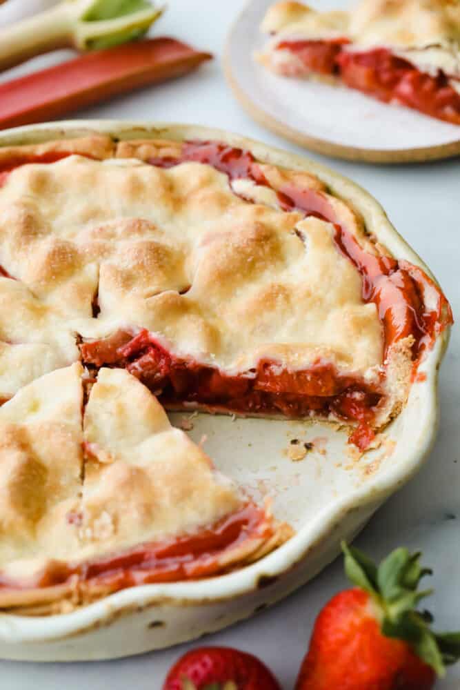 A sweet, tart fruit filling and golden, flaky crust make this Strawberry Rhubarb Pie the dessert of the summer. With a pie this fresh and decadent, you won't want store-bought again! Strawberry rhubarb pie with piece taken out of it