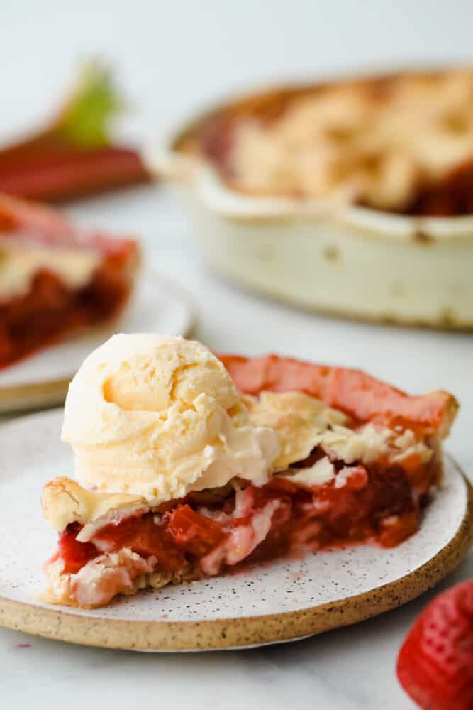 A sweet, tart fruit filling and golden, flaky crust make this Strawberry Rhubarb Pie the dessert of the summer. With a pie this fresh and decadent, you won't want store-bought again! Slice of strawberry rhubarb pie with a scoop of vanilla ice cream on top