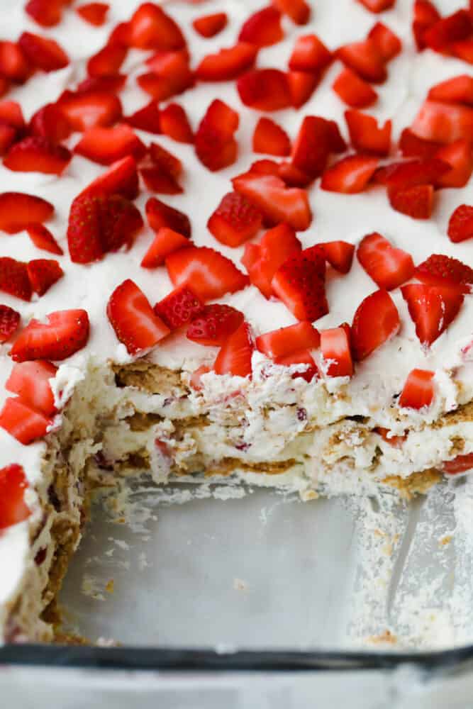 Strawberry Icebox Cake is the cool, creamy, and moist no-bake dessert of your dreams. Add a pop of juicy strawberry and you will never want to make cake another way! Strawberry icebox cake with piece cut out.
