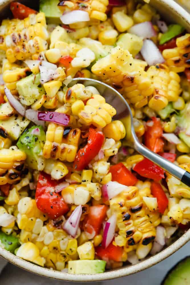 Don't let the name fool you, this Summer Corn Salad definitely can (and should be!) enjoyed all year round! It's a fresh corn salad made with onion, bell pepper, avocado, and.....corn! Fresh or frozen corn will work Spooning a scoop of summer corn salad.