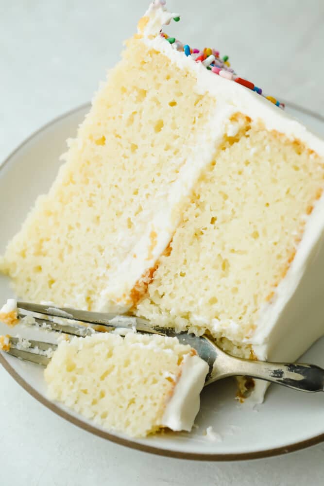 The Absolute Best White Cake is a recipe you will come back to time and time again for a delicious and beautiful result. Fluffy, moist, and soft, this really is a cake to impress! Taking a bite of The Absolute Best White Cake.
