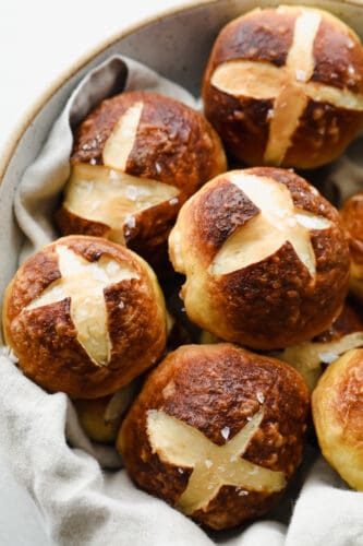 With a soft, tender inside and outside that has that cooked-to-perfection, pretzel texture we all love, these Pretzel Rolls are an instant favorite! Upgrade dinnertime with this irresistible side! Pretzel Rolls topped with coarse salt in a bowl.