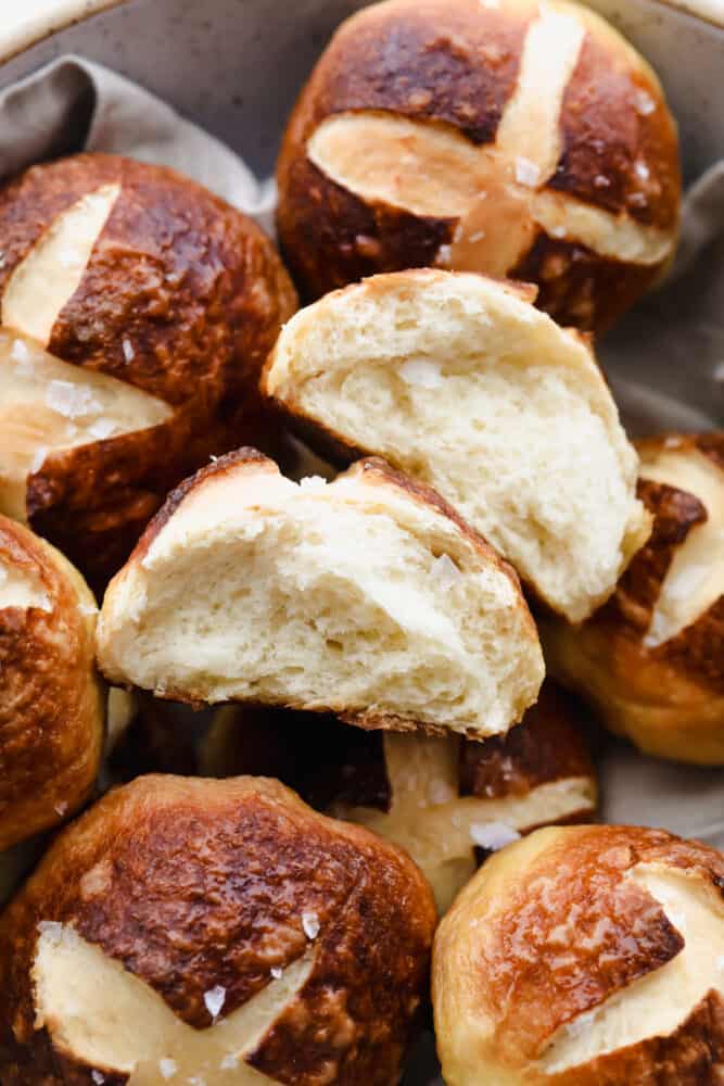 With a soft, tender inside and outside that has that cooked-to-perfection, pretzel texture we all love, these Pretzel Rolls are an instant favorite! Upgrade dinnertime with this irresistible side! Close-up of Pretzel Roll being torn in half.