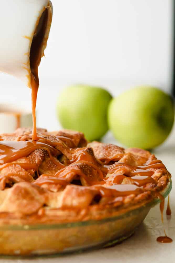 Caramel Apple Pie is the traditional American dessert, but totally elevated. Sour tart apples are smothered in caramel, it's insanely delicious. Pouring the caramel over the apple pie.