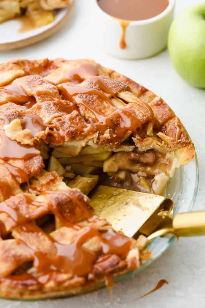 Caramel Apple Pie is the traditional American dessert, but totally elevated. Sour tart apples are smothered in caramel, it's insanely delicious. A slice missing from finished pie.
