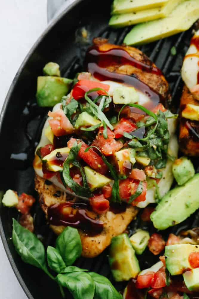 Grilled California Avocado Chicken is tender chicken marinated in an amazing honey garlic balsamic sauce and is grilled to perfection! Upclose picture of chicken topped with the avocado salsa and basil.