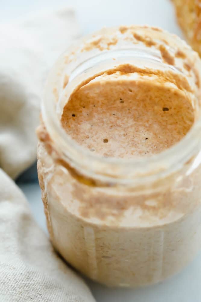 Start your sourdough journey with this guide on cultivating wild yeast! You only need flour, water, and a few minutes of maintenance each day to bake better bread! Jar filled with Sourdough Starter.