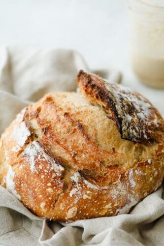 Sourdough Bread is one of the most flavorful, good-for-you loaves of bread out there. Easier than you think with a taste and texture that is absolutely heavenly! Round loaf of sourdough bread.