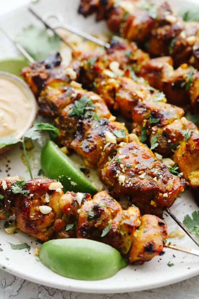 Chicken Satay is juicy, tangy, and absolutely divine. Marinated and then grilled to perfection serve these with a savory peanut sauce that is positively addicting. Chicken on skewers grilled with chopped peanuts for garnish.