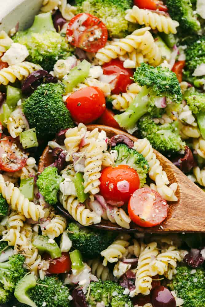 Greek Broccoli Pasta Salad combines tender fusilli pasta with fresh vegetables and a tangy herb dressing. This is the perfect dish to serve with grilled meats, or pack for a picnic or barbecue! Taking a scoop of Greek broccoli pasta salad.