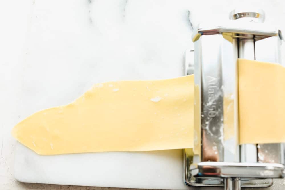 Homemade pasta is a labor of love but it is totally worth the extra work. This pasta is simple and easy, it just takes a bit of time A long golden sheet of pasta getting thinner.