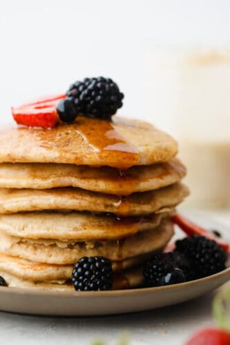 These tried and true Sourdough Pancakes are fluffy and delicious! They pair well with just about any toppings that you have on hand and they have just a touch of sweetness making adding maple syrup the final touch of heaven! A stack of sourdough pancakes with berries on top.