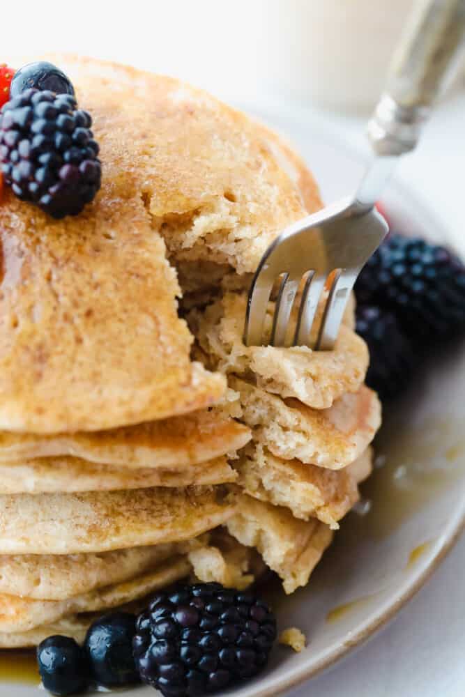 These tried and true Sourdough Pancakes are fluffy and delicious! They pair well with just about any toppings that you have on hand and they have just a touch of sweetness making adding maple syrup the final touch of heaven! Cutting a slice of sourdough pancakes with a fork.
