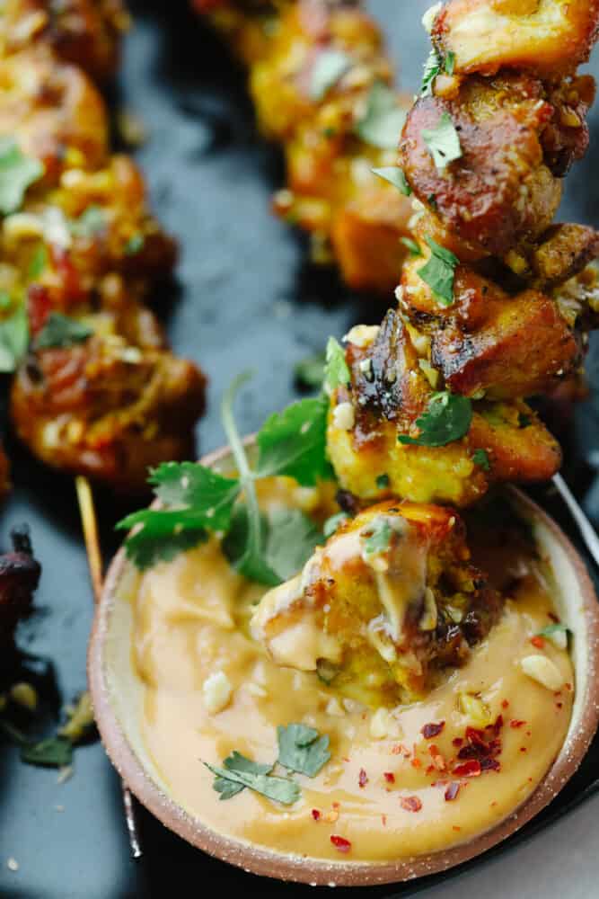 These Thai chicken skewers are marinated in coconut milk, curry and spices and then grilled to perfection. It's a quick and easy meal that's packed full of flavor! Dipping the chicken in homemade peanut sauce.