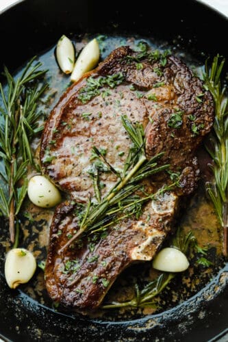 Achieving steakhouse-worthy flavors doesn’t have to be difficult! The ultimate ribeye steak is juicy, flavorful, and seared to perfection all in the comfort of your kitchen. Cooked ribeye steak garnished with rosemary, thyme, and garlic.